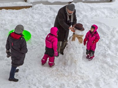 Snögubbe byggs  Äntligen snö 14 februari. Lilian och Ted van Heesch med barnbarn bygger snögubbe på gården.
